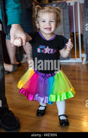 One year old Lily demonstrating her prowess at walking, when Dad gives her a hand Stock Photo