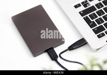 External backup disk hard drive connected to laptop. hard drive backup disk external computer data usb concept Stock Photo