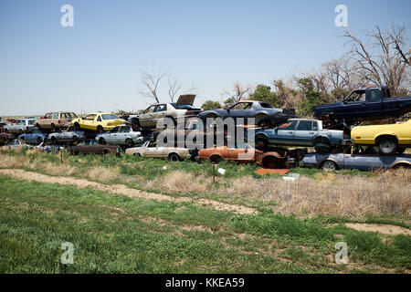 Long line of old obsolete rusting stacked cars in a scrap yard or breakers yard waiting to be crushed and recycled or broken up for parts Stock Photo