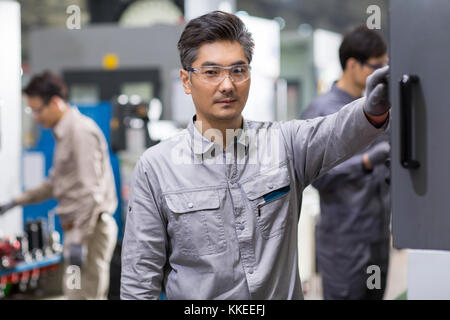 Confident Chinese engineers working in the factory Stock Photo