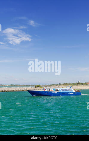 Tourist boat exits the mouth of the Herault River, in Le Grau d'Agde, Herault, Occitanie, France Stock Photo
