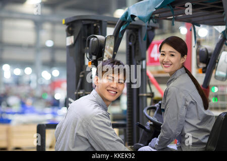 Confident Chinese workers driving forklift in the factory Stock Photo