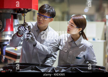 Young Chinese engineers checking machine in the factory Stock Photo