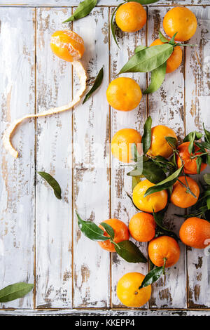 Ripe organic clementines or tangerines with leaves over white wooden plank table as background. Top view, space. Healthy eating Stock Photo