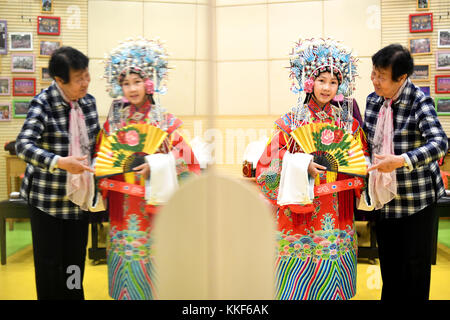 (171205) -- LIUZHOU, Dec. 5, 2017 (Xinhua) -- Li Fusong (1st R), 79, a retired teacher, directs Liang Keyuan, a girl coming from other city, to perform the Peking Opera at the children's center in Liuzhou City, south China's Guangxi Zhuang Autonomous Region, Dec. 2, 2017. Li has been fond of the Peking Opera since childhood, but she didn't get the chance to learn the opera until her retirement in 1994. During her self-study in the following ten years, she found that most of the opera fans were just middle-aged and old people. She then made a resolution to pass on the traditional art to young p Stock Photo