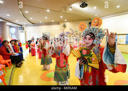 (171205) -- LIUZHOU, Dec. 5, 2017 (Xinhua) -- Li Fusong (2nd L), 79, a retired teacher, watches the Peking Opera performance of children at the children's center in Liuzhou City, south China's Guangxi Zhuang Autonomous Region, Dec. 3, 2017. Li has been fond of the Peking Opera since childhood, but she didn't get the chance to learn the opera until her retirement in 1994. During her self-study in the following ten years, she found that most of the opera fans were just middle-aged and old people. She then made a resolution to pass on the traditional art to young people with her own efforts. Li o Stock Photo