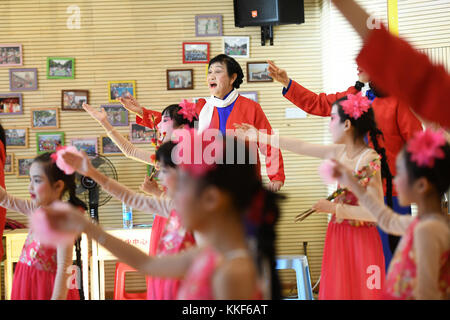 (171205) -- LIUZHOU, Dec. 5, 2017 (Xinhua) -- Li Fusong, 79, a retired teacher, directs children to perform the Peking Opera at the children's center in Liuzhou City, south China's Guangxi Zhuang Autonomous Region, Dec. 3, 2017. Li has been fond of the Peking Opera since childhood, but she didn't get the chance to learn the opera until her retirement in 1994. During her self-study in the following ten years, she found that most of the opera fans were just middle-aged and old people. She then made a resolution to pass on the traditional art to young people with her own efforts. Li opened the Pe Stock Photo