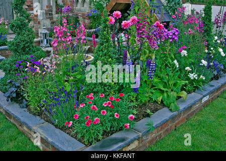 Colourful planting in a raised flower bed of a patio garden Stock Photo