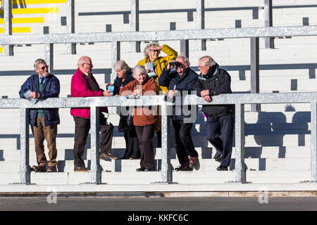 Group of senior retired people enjoy active retirement watching a horse race from the stands at Ffos Las, enjoying day out Stock Photo