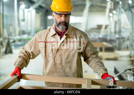 Handsome mature man working in the  modern furniture factory Stock Photo