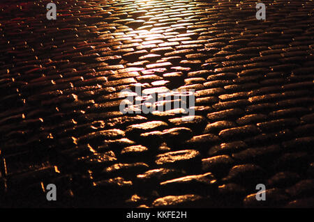 A wet cobbled street shining in sunlight Stock Photo