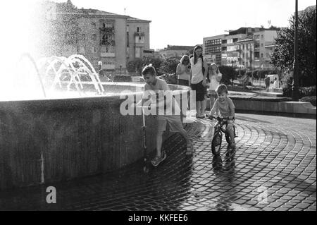 Ivano Frankivsk, Ukraine, June 18, 2017. Race around the fountain. The boys are riding a scooter and a bike. Stock Photo