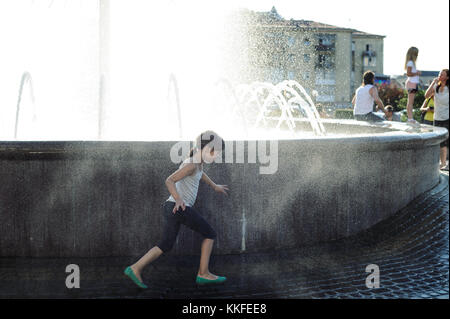 Ivano Frankivsk, Ukraine, June 18, 2017. The seven-year-old girl is runing in a splash of fountain water. Stock Photo