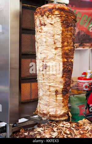 Traditional doner kebab with stacked pork grilling on a rotisserie in front of a vertical element on a street stall in Italy Stock Photo