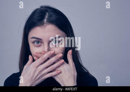 Young brunette woman covering face using her both hands Stock Photo