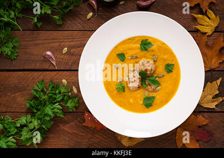 Delicious cream of pumpkin soup with meatballs made of turkey minced meat in a bowl on a wooden table. View from above. Flat lay. Top view. Thanksgivi Stock Photo