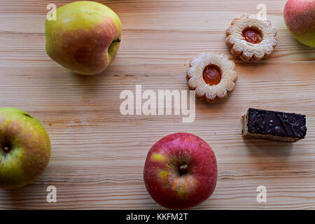 Red/green apples and pair of cookies on wooden background Stock Photo