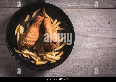 Fried chicken legs and french fries in the pan,blank space on the right side Stock Photo