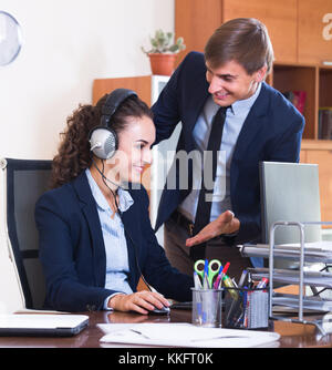 Smiling customer support team working in call centre. Focus on woman Stock Photo
