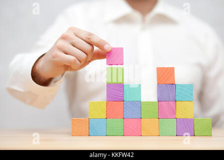 Man's hand stacking colorful wooden blocks. Business development concept Stock Photo