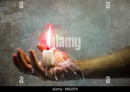 A hand holding a burning candle and wax falling down Stock Photo