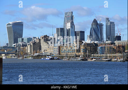 The London City skyline contrasts with warehouses and moored sailing barges on the waterfront in Wapping. Viewed from Bermondsey. UK Stock Photo