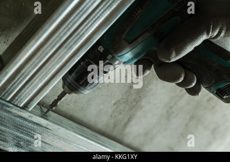 Man assembles profile metal frame for plasterboard ceilings Stock Photo