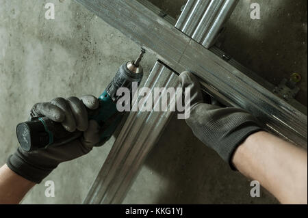 Man assembles profile metal frame for plasterboard ceilings Stock Photo