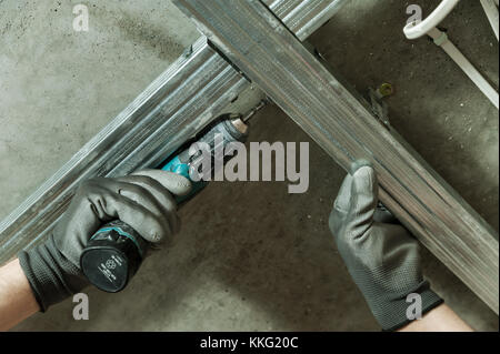 Man assembles profile metal frame for plasterboard ceilings Stock Photo