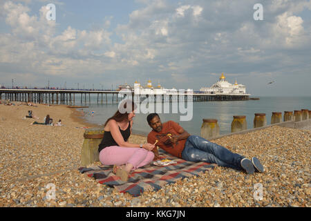 A couple eating chips on Eastbourne beach, East Sussex, England, UK Stock Photo