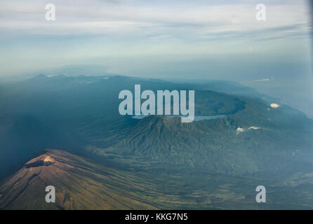 Mount Agung seen from airplane window early morning flight from Denpasar to Makassar. Mount Batur and its massive caldera seen in the background. Stock Photo