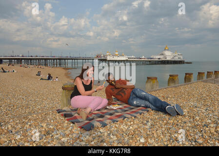 A couple eating chips on Eastbourne beach, East Sussex, England, UK Stock Photo