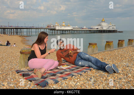 A couple eating chips on Eastbourne beach, East Sussex, England, UK Stock Photo