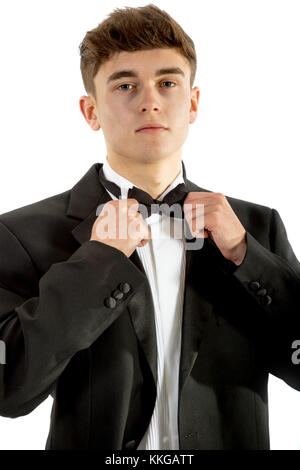 18 year old wearing a tuxedo adjusting his bowtie isolated on a white background Stock Photo