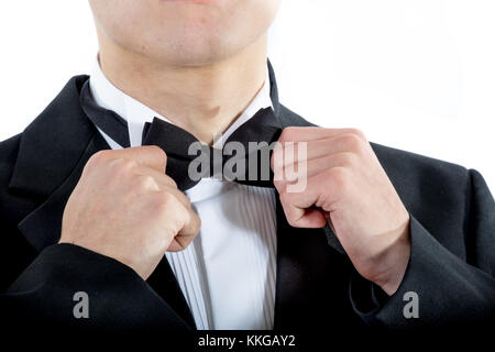 18 year old wearing a tuxedo adjusting his bowtie isolated on a white background Stock Photo