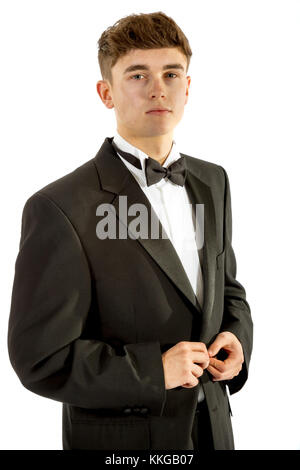 18 year old wearing a tuxedo doing up his jacket isolated on a white background Stock Photo