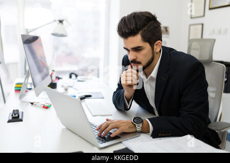 Young handsome architect working on laptop in office Stock Photo