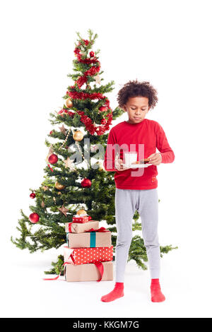 Mixed race boy near Christmas tree Stock Photo