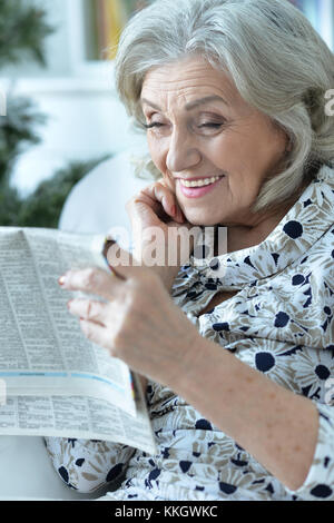 Aged  woman reading newspaper Stock Photo