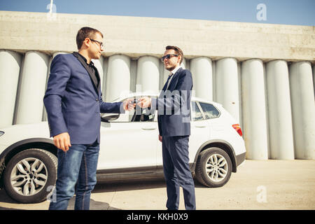 car sales. one person sells car and gives the key to the new owner Stock Photo