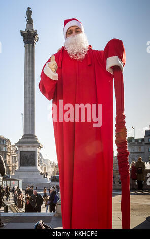 London, UK. 1st Dec, 2017. A floating Santa street performer stands tall near Nelson’s Column on a cold but sunny afternoon in Trafalgar Square. Credit: Guy Corbishley/Alamy Live News Stock Photo