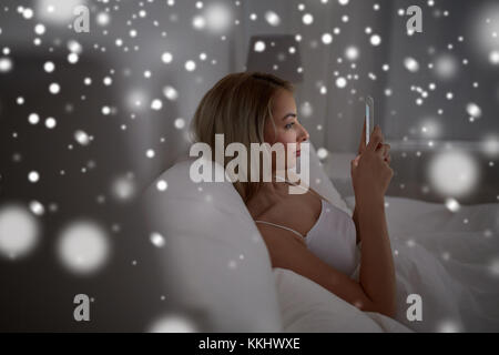 young woman with smartphone in bed at home bedroom Stock Photo