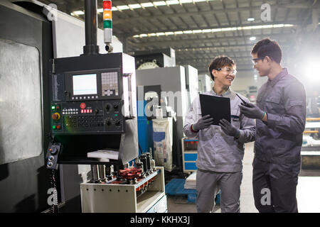 Confident Chinese engineers talking in the factory Stock Photo