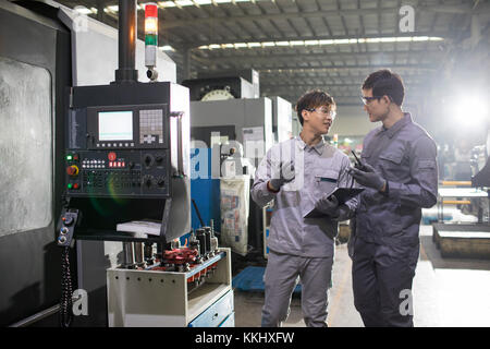 Confident Chinese engineers talking in the factory Stock Photo