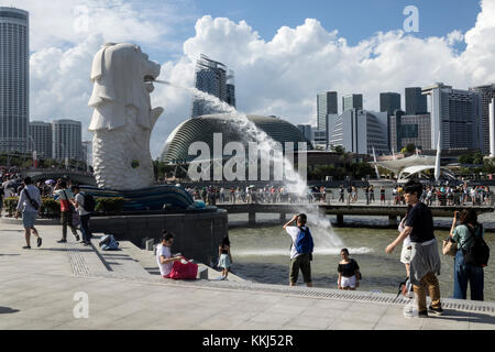 Tourists looking at the iconic lion display fountain at Merlion Park, One Fullerton, Singapore. It has been in this location since 2002 Stock Photo