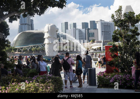 Tourists looking at the iconic lion display fountain at Merlion Park, One Fullerton, Singapore. It has been in this location since 2002 Stock Photo