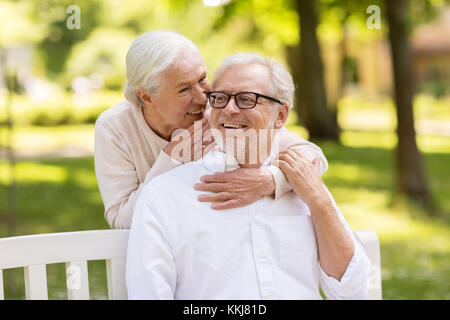 happy senior couple sitting on bench at park Stock Photo