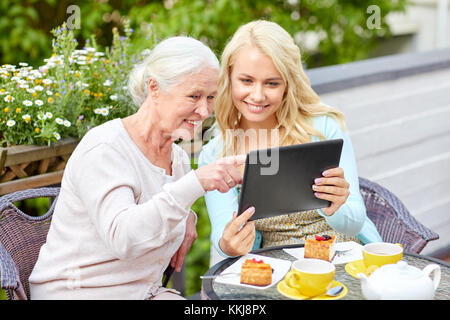 daughter with tablet pc and senior mother at cafe Stock Photo