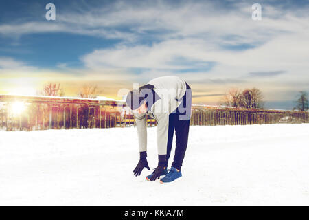 man exercising and stretching leg on winter bridge Stock Photo