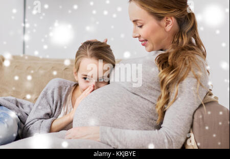 pregnant woman and girl talking to baby in belly Stock Photo